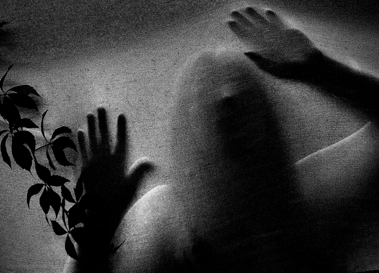 Mysterious figure with hands pressed against frosted glass, evoking a spooky atmosphere.